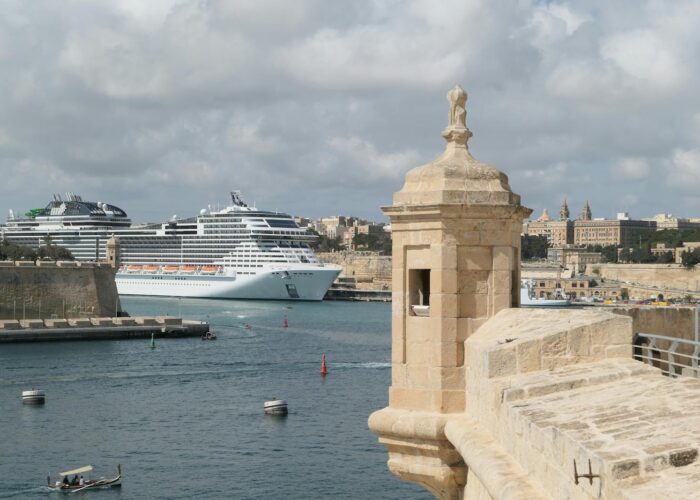 A beautiful view of cruise ships docking at Birgu Harbor, Malta, with historic architecture in view.